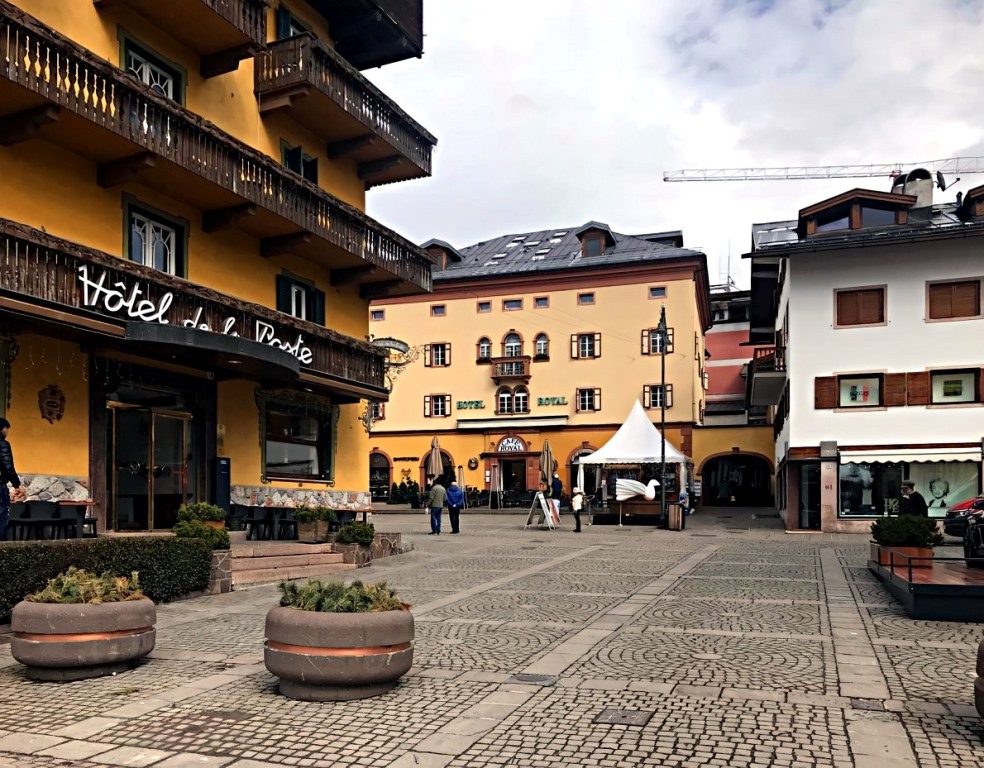 Hotel De La Poste — 4-звёздочный отель в центре горнолыжного курорта Кортина д'Ампеццо. Адрес: Piazza Rom, 14, Италия, Кортина д'Ампеццо. В отеле: бар/кафетерий; 2 ресторана; терраса; зал с креслами 70-х годов; парковка. В номерах: мини-бар, спутниковое ТВ, прямой телефон, Data port, полностью оборудованная ванная с феном, балкон. В обоих ресторанах отеля к услугам гостей меню «а-ля карт» и безглютеновые блюда. Здесь подают региональные блюда Венето, блюда интернациональной кухни, а также местные вина. В 20 метрах от отеля находится остановка горнолыжного автобуса, примерно за 5 минут можно доехать до ближайших лыжных трасс.